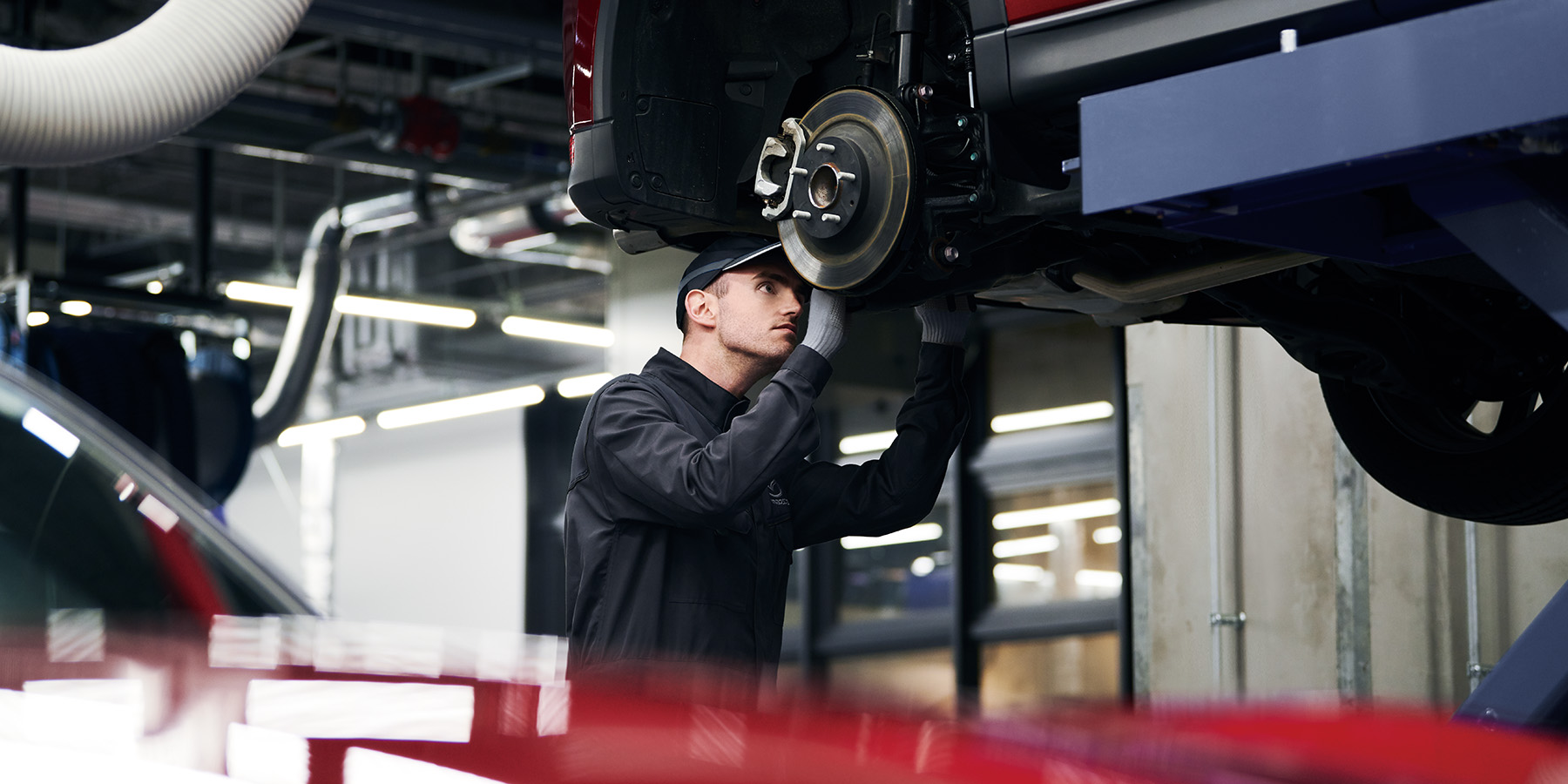 Automotive technician checking underneath a Mazda vehicle